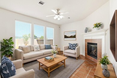 Bright family room with tile flooring, gas-log fireplace, and wall of windows overlooking the backyard. **Virtually Staged**
