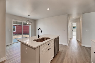 Kitchen with white cabinetry, hanging light fixtures, light wood finished floors, recessed lighting, and stainless steel dishwasher