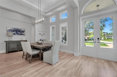 Dining area with an inviting chandelier, baseboards, french doors, and light wood-type flooring