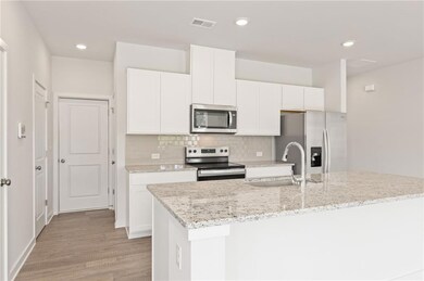 Kitchen featuring stainless steel appliances, a sink, white cabinetry, an island with sink, and recessed lighting