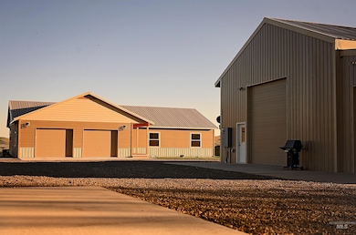View of front of property featuring an attached garage, an outbuilding, and gravel driveway