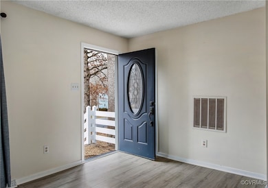 Entryway with a textured ceiling and light hardwoo