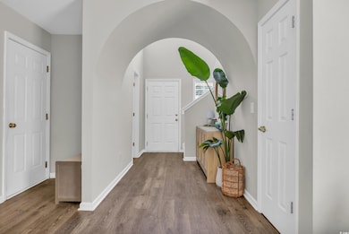 Foyer entrance with wood finished floors, arched walkways, and baseboards