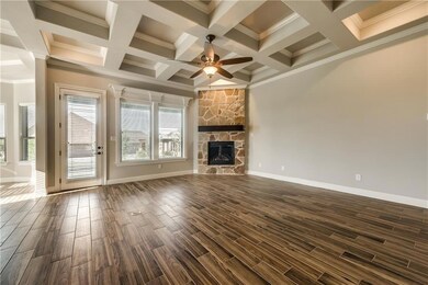 Unfurnished living room featuring crown molding, baseboards, ceiling fan, wood finish floors, and a stone fireplace