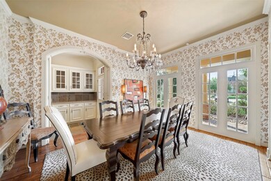 Entertain in style in this formal dining room with crown moulding, crystal chandelier lighting, windows with transoms & hardwood floors.