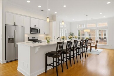 Kitchen with appliances with stainless steel finishes, light wood-style floors, light countertops, decorative backsplash, and a kitchen bar