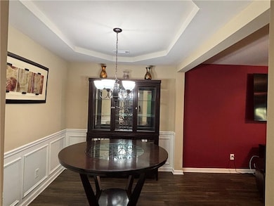 Foyer entrance featuring a raised ceiling, a chandelier, and dark wood-type flooring