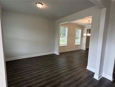 Spare room with dark wood-style floors, a chandelier, baseboards, and ornamental molding