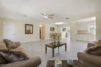 Living room with visible vents, a ceiling fan, bas