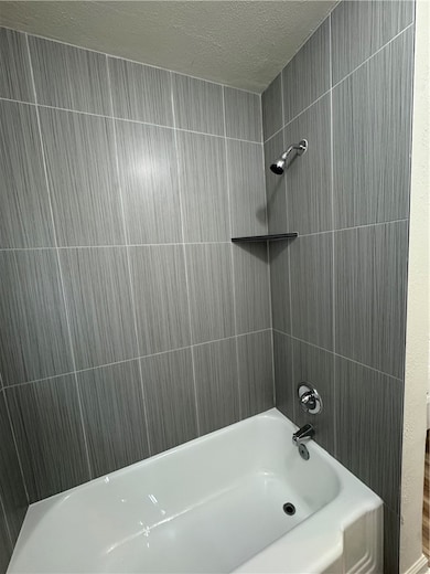 Full bath featuring a textured ceiling and bathtub