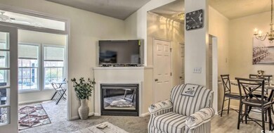 Carpeted living room with a glass covered fireplac