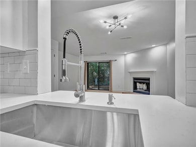 Kitchen featuring backsplash, a fireplace, light stone countertops, open floor plan, and recessed lighting