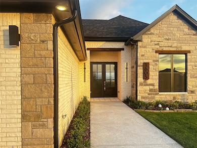 Doorway to property with a shingled roof, french doors, and brick siding