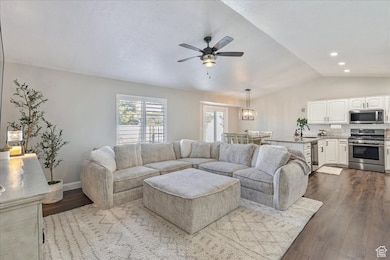 Living room with lofted ceiling, dark wood-type flooring, and a ceiling fan