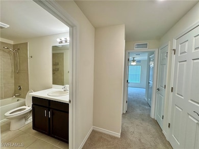 Hallway showing Full bath featuring toilet, shower / bathing tub combination, visible vents, ceiling fan, and vanity