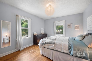 Bedroom featuring multiple windows, light wood-style floors, and a textured ceiling