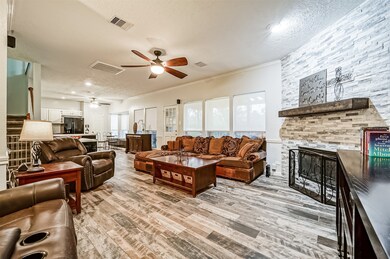 The family room is anchored by a gas log fireplace with a stylish floor-to-ceiling stacked stone fireplace and a cedar beam mantle. Also note the wall of rear-facing windows with light filtering roller shades.