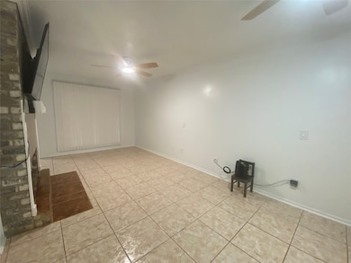 Spare room with a ceiling fan, a brick fireplace, and light tile patterned floors