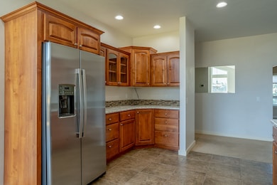 Kitchen featuring stainless steel fridge with ice dispenser, brown cabinets, and granite counters