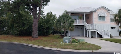 Raised beach house with stairs, driveway, and a garage