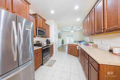 Kitchen with stainless steel appliances, recessed lighting, brown cabinetry, light countertops, and light tile patterned floors