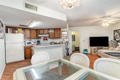 Kitchen with a textured ceiling, white appliances,