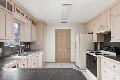 Kitchen with visible vents, white appliances, under cabinet range hood, a sink, and backsplash