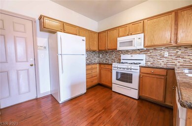 Kitchen features white appliances, hardwood floors