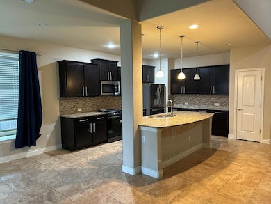 Kitchen featuring dark cabinets, light stone counters, black appliances, and recessed lighting