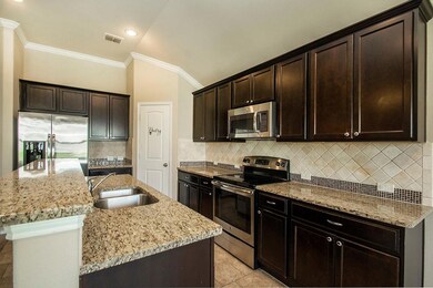Kitchen featuring appliances with stainless steel finishes, vaulted ceiling, sink, decorative backsplash, and an island with sink