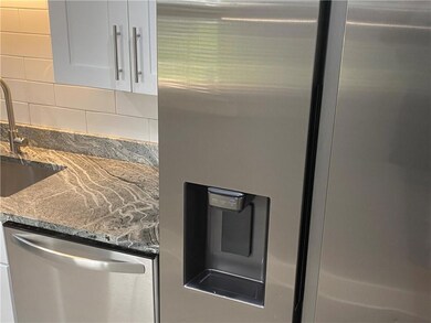 Kitchen view of appliances with stainless steel finishes, decorative backsplash, white cabinets, a sink, and light stone counters