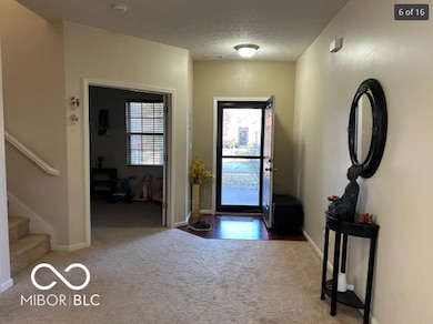 carpeted foyer with stairs and a textured ceiling