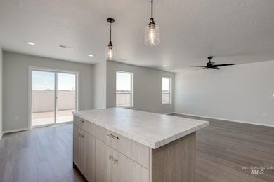 Kitchen with open floor plan, dark wood-style floors, light countertops, and pendant lighting