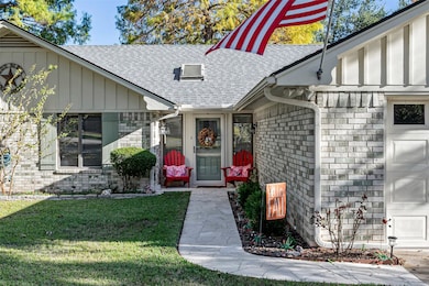 Doorway to property with brick siding, roof with shingles, a lawn, and board and batten siding