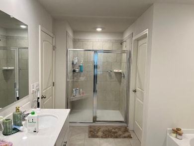Full bathroom with vanity, light tile patterned floors, and a shower stall