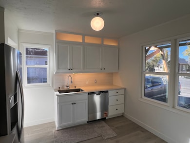 Kitchen featuring stainless steel appliances, white cabinetry, tasteful backsplash, dark wood finished floors, and ornamental molding
