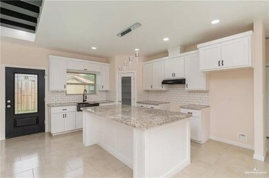 Kitchen featuring under cabinet range hood, tasteful backsplash, white cabinets, light stone counters, and recessed lighting