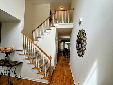 Stairway with wood finished floors, a chandelier, and a high ceiling