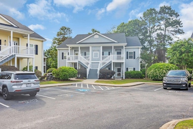 View of property with uncovered parking and stairs