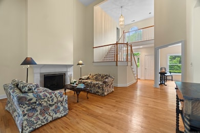 Sophisticated and sunlit: This elegant living room features gleaming hardwood floors, a cozy fireplace, and an open staircase leading to two upstairs bedrooms-blending warmth and architectural charm.