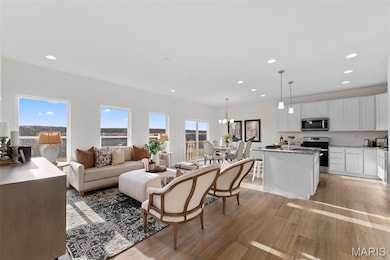 Living area featuring light wood finished floors, recessed lighting, and a chandelier
