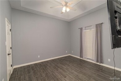 Spare room with ceiling fan, baseboards, and dark wood-type flooring