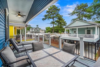Wooden terrace with ceiling fan, outdoor dining area, and a residential view