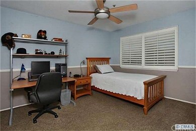 Secondary bedroom with ceiling fan and shutters an