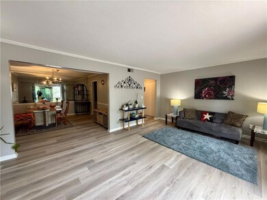 Living area featuring ornamental molding, a chandelier, wood finished floors, and baseboards