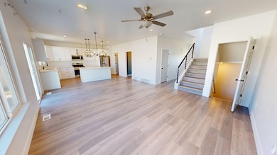 Unfurnished living room with stairs, recessed lighting, light wood-style floors, a chandelier, and ceiling fan