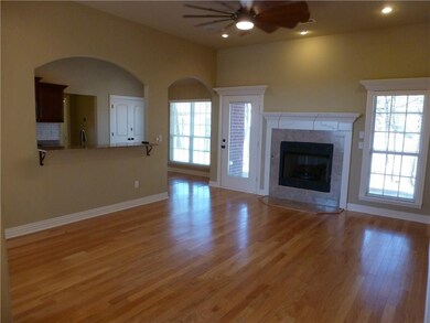 View of layout from entry. Gas log fireplace, access to back patio, pass through from kitchen to living room and those beautiful hardwood floors.