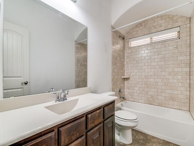 Full bathroom featuring vanity, tile patterned flooring, toilet, and tiled shower / bath