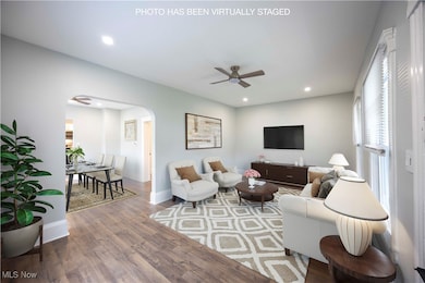 Living room with arched walkways, wood finished floors, ceiling fan, and recessed lighting