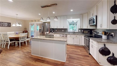 Kitchen featuring stainless steel appliances, backsplash, white cabinets, a kitchen island, and crown molding